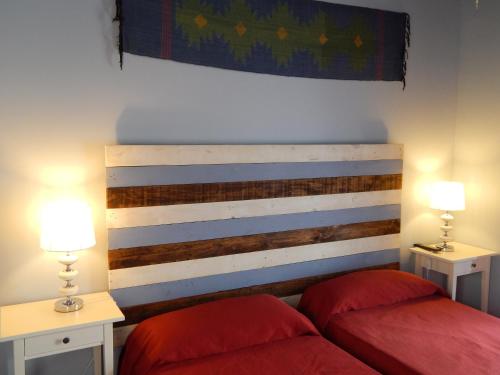 加的斯霍斯佩德利亚马尔克斯酒店的一间卧室配有两张红色的床和两盏灯。