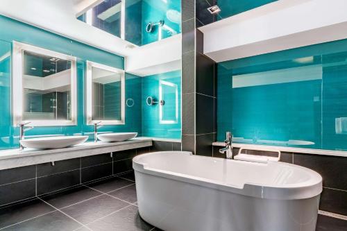 卑尔根卑尔根皇家丽笙酒店的蓝色的浴室设有两个盥洗盆和一个浴缸。