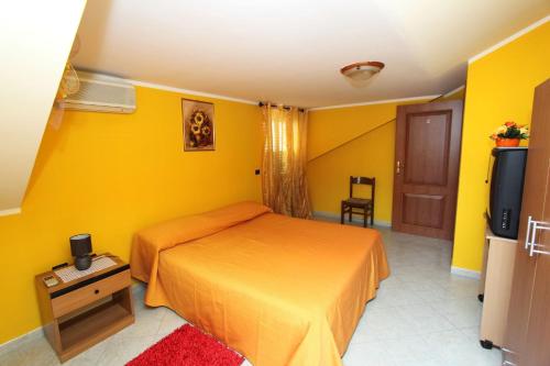 维博瓦伦蒂亚码头Bed and Breakfast Vibo Mare的一间卧室设有黄色的墙壁、一张床和电视