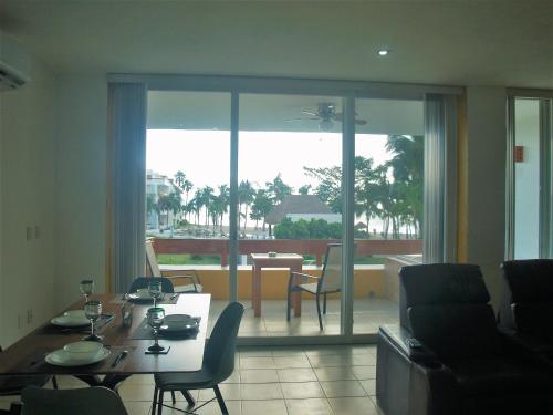 科苏梅尔Beachfront Apartment Your Home in Cozumel的一间带桌椅的客厅和一个阳台