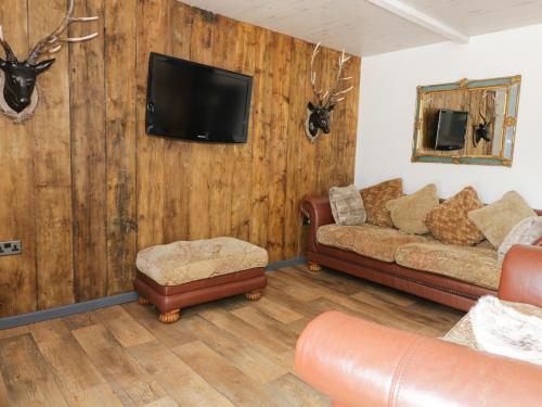 霍舍姆圣斐德Foxley Wood Cottage的客厅配有沙发和墙上的电视