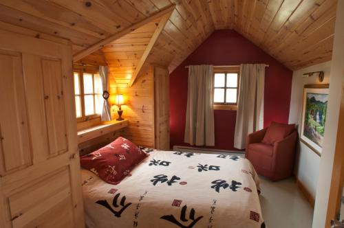 拜圣保罗Chalet Paradis de Charlevoix的小木屋内的卧室,配有一张床和椅子