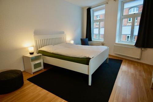 维斯马Ferienwohnung Badstaven的卧室配有白色的床和2扇窗户。