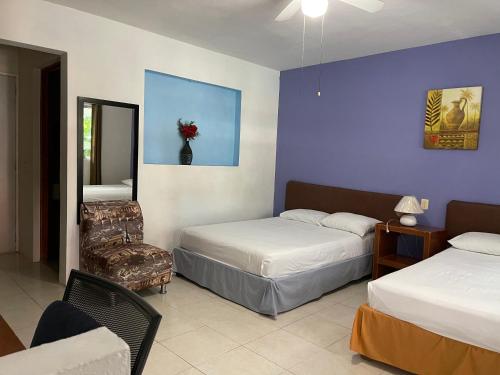 坎佩切Hotel Villa Escondida Campeche的一间卧室配有两张床、一把椅子和镜子