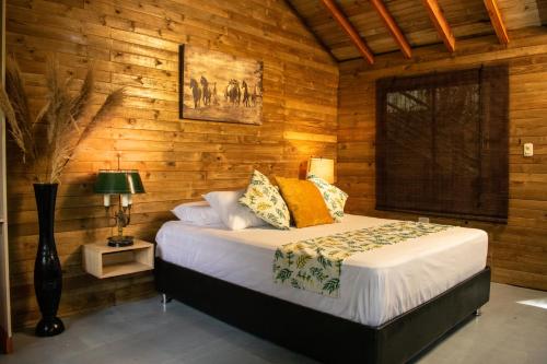 CalabazoHotel Pony Club La Vecindad Tayrona - Zaino的卧室配有木墙内的一张床