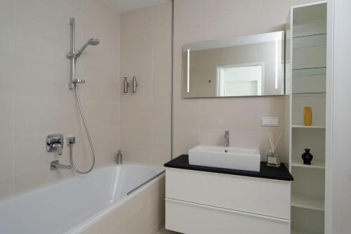 维也纳Triiiple Suites Level 21 mit Balkon und Tiefgarage的带浴缸、水槽和镜子的浴室
