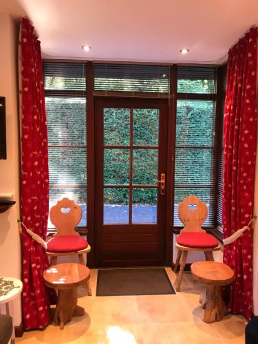卢特伦Romantisch Gastenverblijf 'Het Vogelhuisje'的门前两把椅子和红色靠垫