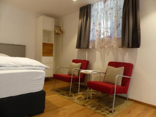因斯布鲁克Gstill-4-Living的一间卧室配有两张红色椅子和一张床