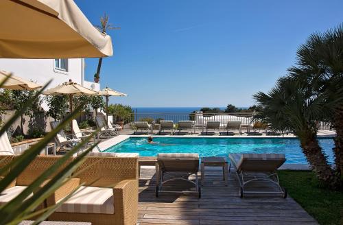 卡普里卡纳斯塔酒店的一个带椅子和桌子的游泳池以及一把遮阳伞