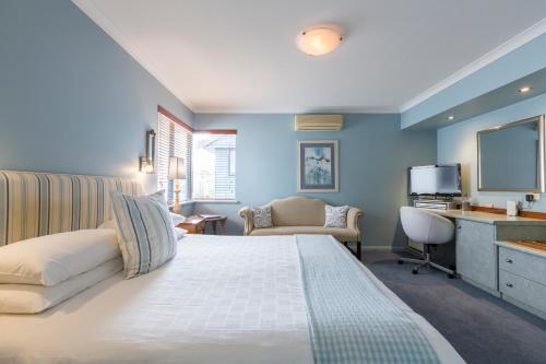 奥尔巴尼湾畔海滩酒店的一间卧室配有一张床、一张书桌和一台电视。