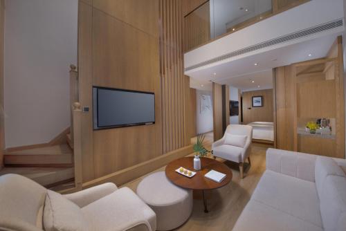 淳安voco千岛湖阳光大酒店的客厅配有沙发和墙上的电视