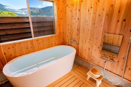 由布市Cominka Yufuin的带浴缸的木制浴室设有窗户