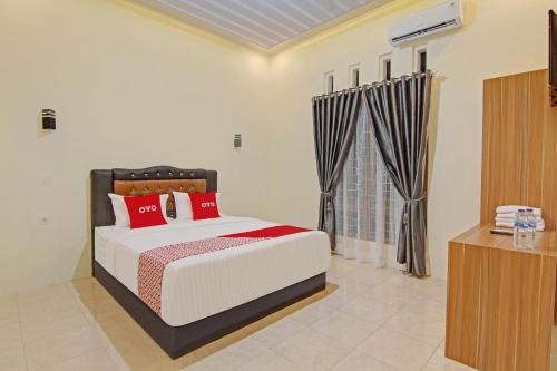 巴东Capital O 90643 Suri Guest House Syariah的一间卧室配有一张带红色枕头的大床