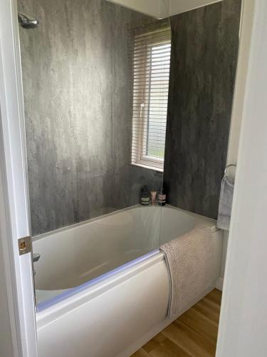 布德Morwenna Lodge的带窗户的浴室内的白色浴缸