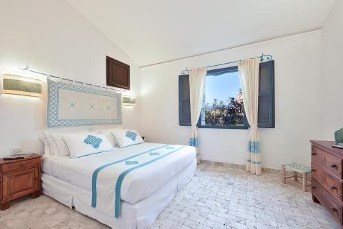 阿尔巴塔克斯Arbatax Park Resort - Borgo Cala Moresca的卧室设有一张白色大床和一扇窗户。