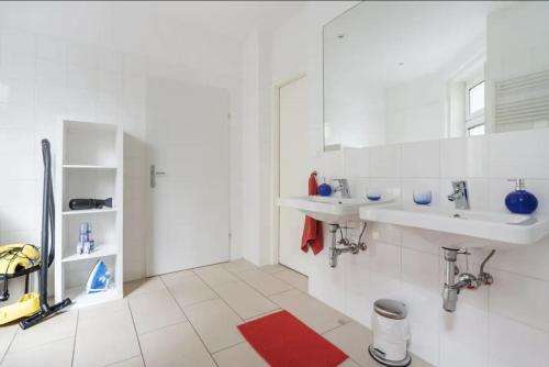 维也纳Apartment France | Operastreet的白色浴室设有两个水槽和红色地毯。