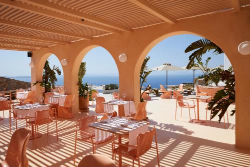 法纳里Collini Suites & Villas Mykonos的一间设有桌椅的海洋餐厅