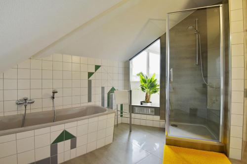 鲁多尔施塔特Studioappartment SAALEBLICK的带浴缸和玻璃淋浴间的浴室。