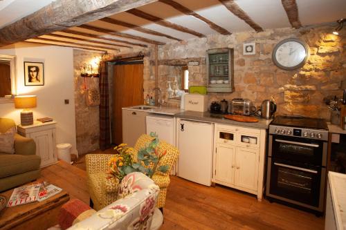 Weston Subedge帕普福斯特谷仓度假屋的厨房以及带墙上时钟的客厅。