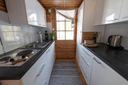SaariharjuMetsä Kolo的厨房配有白色橱柜、水槽和窗户。