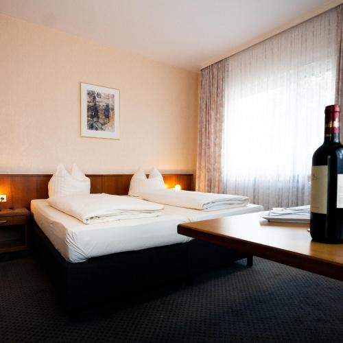 曼海姆魏格纳酒店的酒店客房带两张床和一瓶葡萄酒