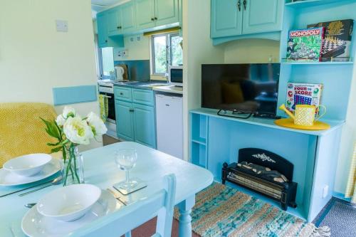 Napton on the HillWind In The Willows: Sleeps 4, Kitchen, bathroom, lounge, WIFI的厨房配有蓝色橱柜和白色的鲜花桌