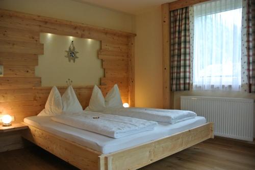 海利根布卢特Pension und Apartment Edelweiß的一间卧室配有一张带白色床单的床和一扇窗户。