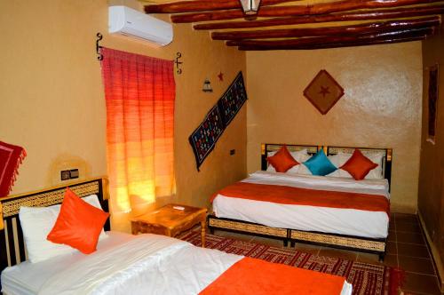 梅尔祖卡奥贝吉诺士酒店的一间卧室配有两张带橙色和蓝色枕头的床