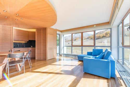 塞斯特雷Terrazza su Sestriere Lux的一间带蓝色沙发的客厅和一间厨房