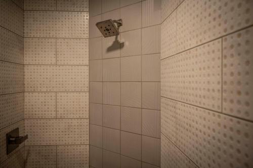 印第安纳波利斯Hotel Broad Ripple的浴室内铺有白色瓷砖并配有淋浴头的淋浴间