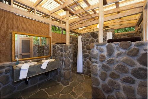 Waipio Valley Botanical Garden的石质浴室设有两个水槽和镜子