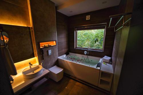 瓦亚纳德Jungle Bay Resorts & Spa的带浴缸、水槽和窗户的浴室