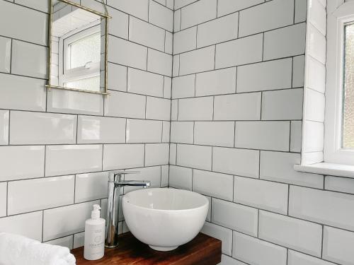 塔伯特Old Pier Cottage Tarbert的白色瓷砖浴室设有水槽和镜子