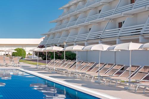 沃迪切奥林匹亚酒店的游泳池旁的酒店拥有椅子和遮阳伞