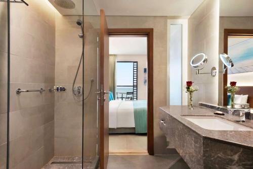 阿吉曼Wyndham Garden Ajman Corniche的带淋浴、盥洗盆和镜子的浴室