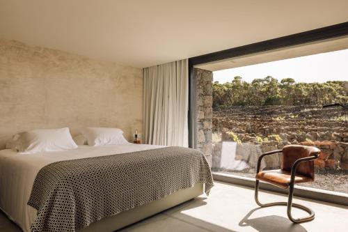 Cais do MouratoAzores Wine Company的卧室配有床、椅子和窗户。