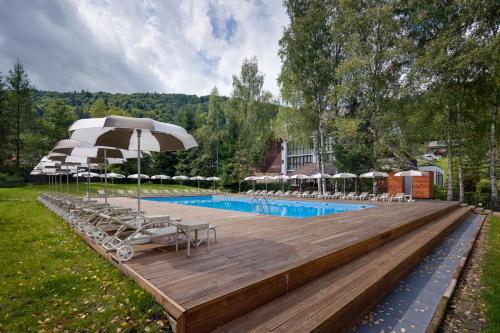 亚列姆切亚列姆切俱乐部酒店的木制甲板上配有椅子和遮阳伞的游泳池