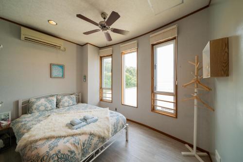 恩纳ペンション ラナカイハウス沖縄的一间卧室配有一张带吊扇的床