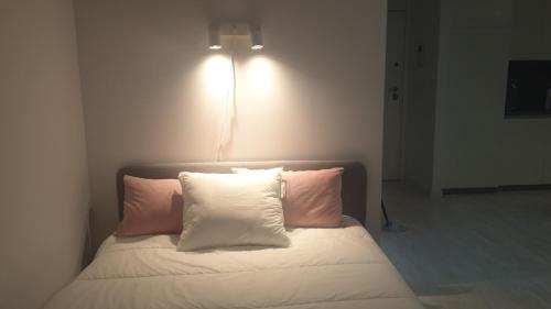 马尼塞斯aeropuerto loft polígono的一张带两个枕头的床和墙上的灯