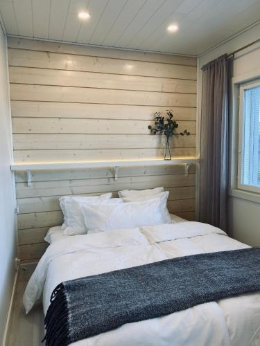 瓦萨Ihana asunto - The Nest with Sauna in VAASA的卧室配有一张白色大床和木墙