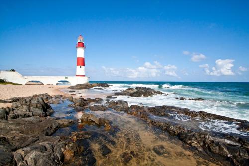 萨尔瓦多Kitnets com AR Condicionado na Praia的岩石海滩上的红白色灯塔