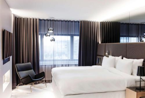 赫尔辛基赫尔辛基丽笙布鲁皇家酒店的酒店客房带一张大床和一把椅子