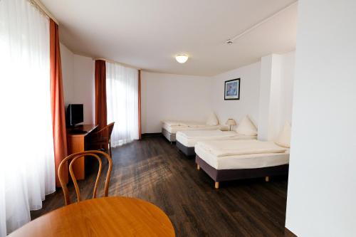 塞恩德森德公寓式酒店的带三张床和桌椅的房间