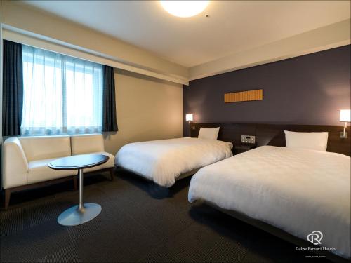 筑波筑波大和鲁内酒店的酒店客房设有两张床、一张桌子和一个窗户。