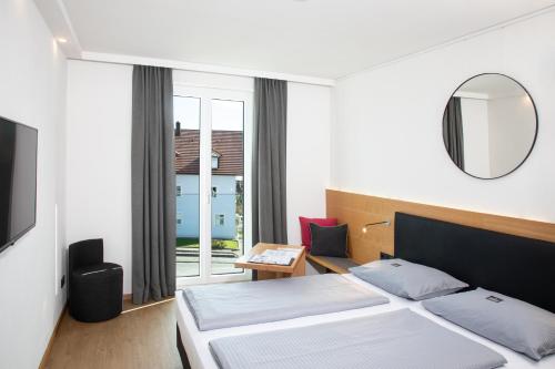 因河畔辛巴赫因河畔辛巴赫汽车旅馆的一间卧室配有一张床、镜子和窗户