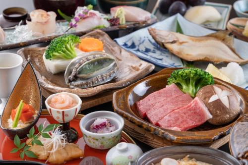 鹤冈市Ikkyu -Seaside Hotel-的餐桌上放着蔬菜和肉类食品