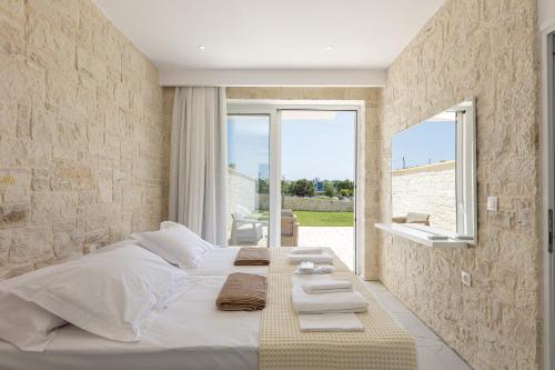 丹诺尼Mythos villas的卧室设有一张白色大床和一扇窗户。