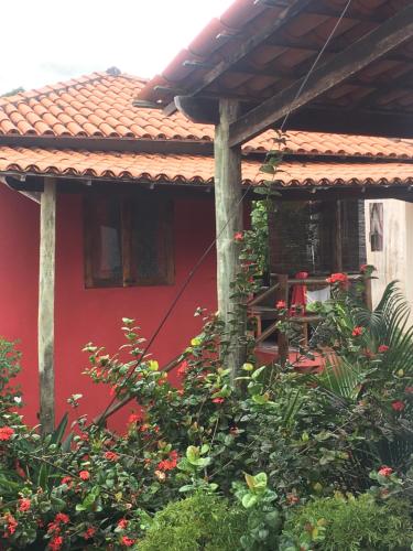 伊塔卡雷Vila Hibisco Itacaré的红色的房子,有红色的屋顶和一些植物