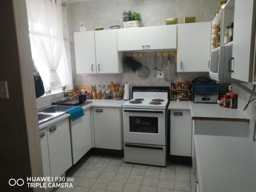 比勒陀利亚Private Room Chez Khanyi Homestays的厨房配有白色橱柜和炉灶烤箱。