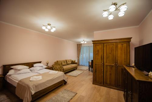 AnieşCasa Măiereană的一间卧室配有一张床、一台电视和一张沙发